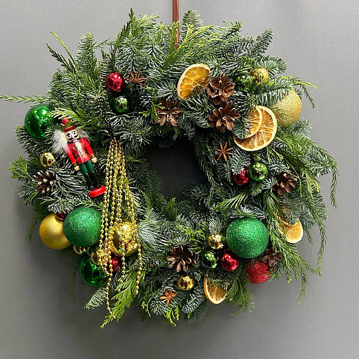 Новогодний венок с разноцветным декором и Щелкунчиком по лучшей цене в Москве Новогодний венок с разноцветным декором и Щелкунчиком с доставкой в Москве