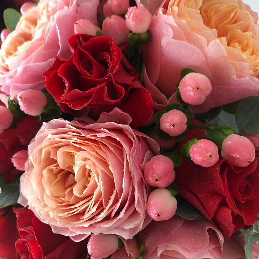 Букет из персиковых пионовидных роз, красных кустовых роз, гиперикума и эвкалипта